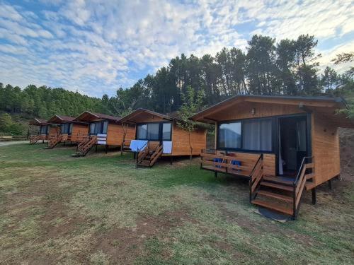 a row of wooden huts in a field at Wooden Villas Karme in Koman