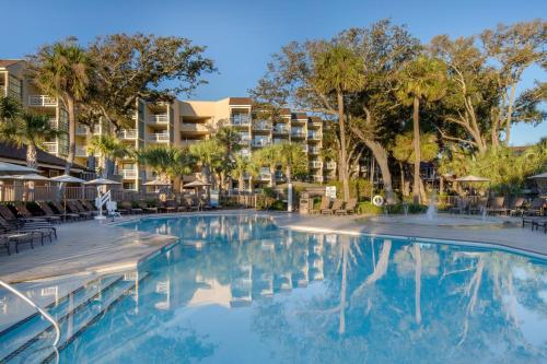 a swimming pool at a resort with chairs and trees at Omni Hilton Head Oceanfront Resort in Hilton Head Island