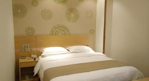 a bedroom with a large white bed with a wooden headboard at GreenTree Inn Xi'an Terracotta Warriors Huaqing Pool Metro Station in Xi'an
