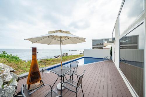 a patio with a table and an umbrella and the ocean at Ocean Bliss in Ulsan