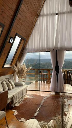 a living room with a bed and a large window at Chales alto do morro 1, conforto e vista privilegiada in Rancho Queimado