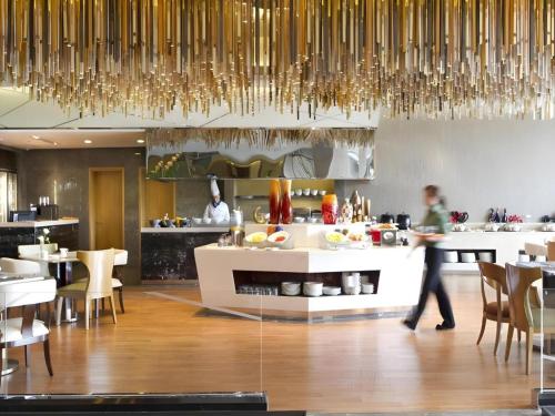 a person walking in a kitchen with a table at Dusit D2 Binhu Changzhou Hotel in Changzhou