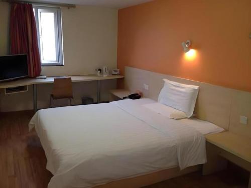 a bedroom with a large white bed and a desk at 7 Days Inn Qingdao Liaoyang West Road Xinye Plaza Metro Station in Qingdao
