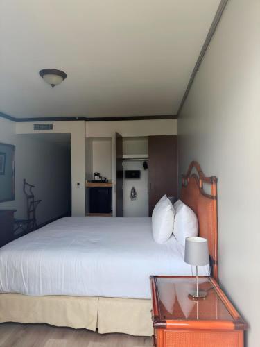 a bedroom with a white bed and a table with a lamp at Radisson Colon 2,000 Hotel & Casino in Colón