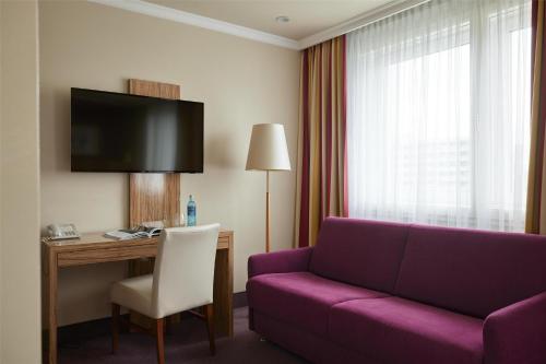 a living room with a purple couch and a desk at Best Western Raphael Hotel Altona in Hamburg