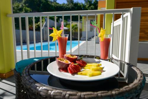 a plate of fruit on a table with two cocktails at LE MALAYA in Saint-Joseph