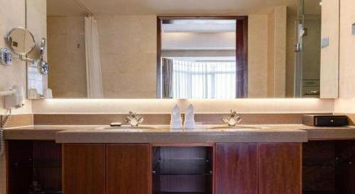 a bathroom with a sink and a large mirror at Qingdao Blue Horizon Hotel Licang in Qingdao