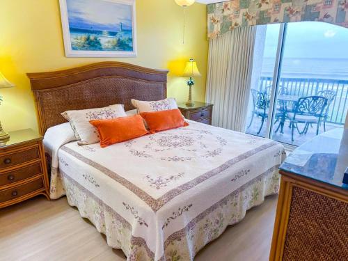 a bedroom with a bed with orange pillows and a balcony at Ashworth 303 in North Myrtle Beach