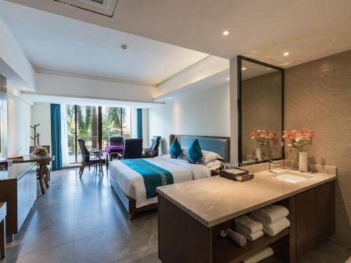 a bedroom with a bed and a bathroom with a sink at Da Peng Zhongzhou Hotel in Haikou