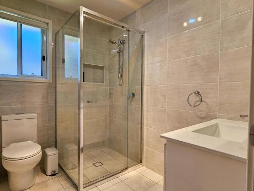 a bathroom with a shower and a toilet and a sink at Summer Villa in Kiama