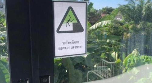 a sign in front of a window of a garden at Near beach hostel in Bang Tao Beach