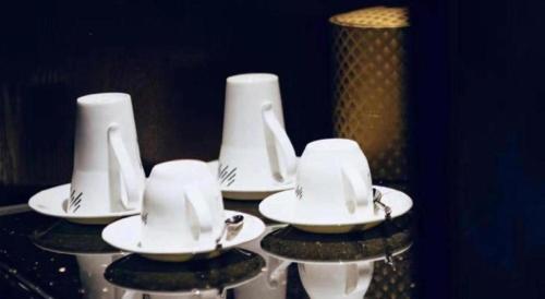 four white plates and napkins sitting on a table at Manhatton Hotel Beihai in Beihai