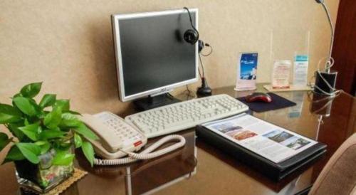 a desk with a computer and a phone on it at Chinflux Mandarin Hotel in Dongguan