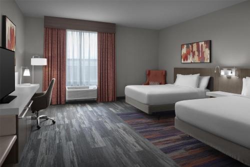 a hotel room with two beds and a desk at Hilton Garden Inn Charlotte Waverly in Charlotte