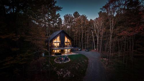 a house in the middle of a forest at night at Spa and Billard - Chalet Le Silverson in Brownsburg