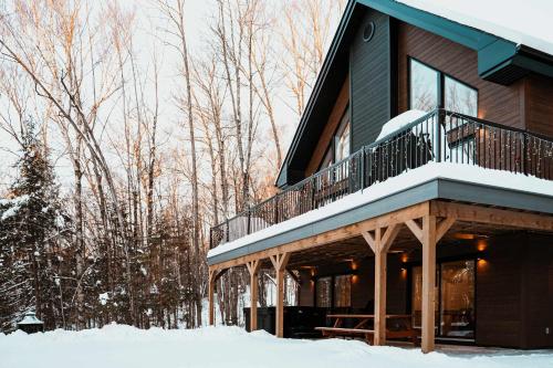 a house with a deck in the snow at Spa and Billard - Chalet Le Silverson in Brownsburg