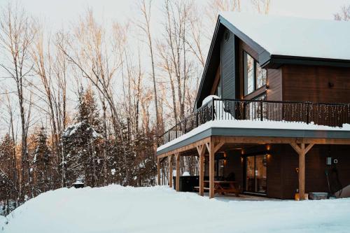 a house with a deck in the snow at Spa and Billard - Chalet Le Silverson in Brownsburg