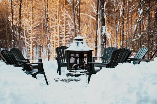a group of chairs and a lantern in the snow at Spa and Billard - Chalet Le Silverson in Brownsburg