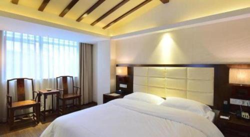 a bedroom with a large white bed and a window at Oriental Hotel in Dongguan
