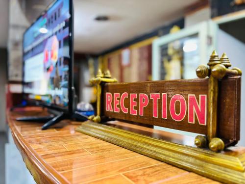 a sign that says reception on a wooden table at โรงแรมรอยัลจอมมณี เฮอริเทจ in Ban Na Kai