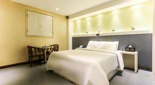 a bedroom with a large white bed and a table at Seven Motel Ansan in Ansan