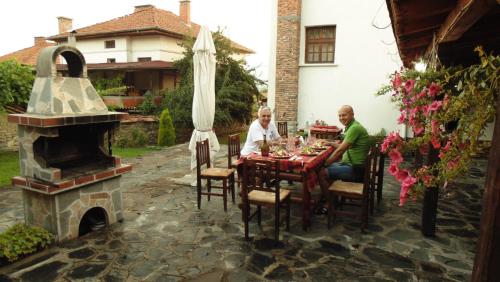 two people sitting at a table with a fireplace at Guest House Popov in Marchevo