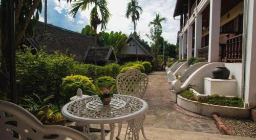 a patio with a table and chairs next to a building at The View Pavilion Hotel in Luang Prabang