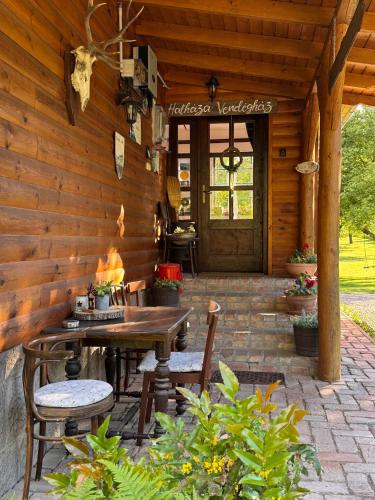 a patio with a table and chairs and a wooden wall at Halháza vendégház in Sirok