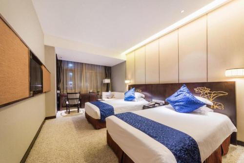 a hotel room with two beds with blue pillows at Dajiuhua Hotel in Chizhou