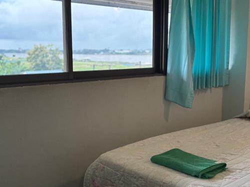 a bedroom with a bed with a green pillow next to a window at โรงแรมรอยัลจอมมณี เฮอริเทจ in Ban Na Kai