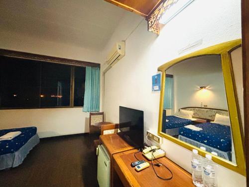 a room with a bedroom with a bed and a mirror at โรงแรมรอยัลจอมมณี เฮอริเทจ in Ban Na Kai