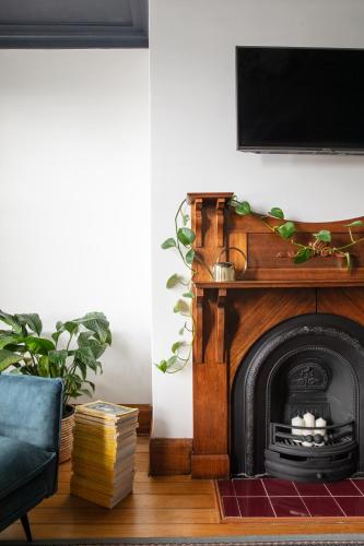 a living room with a fireplace with a tv above it at Cable's Landing, stunning heritage home near the Cataract Gorge and CBD in Royal Park