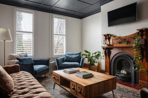 a living room with a coffee table and a fireplace at Cable's Landing, stunning heritage home near the Cataract Gorge and CBD in Royal Park