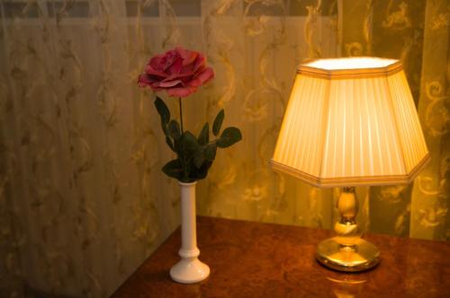 a red rose in a white vase next to a lamp at Weena House in Rotterdam