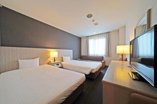 a hotel room with two beds and a flat screen tv at Chisun Hotel Kamata in Tokyo