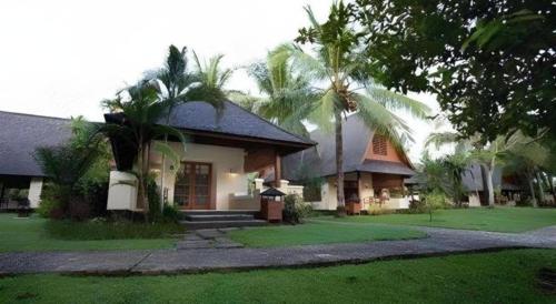 a house with palm trees in front of it at Tanjung Lesung Beach Hotel in Carita