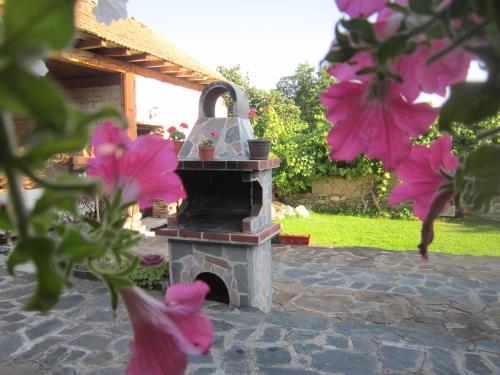 a stone fireplace in a yard with pink flowers at Guest House Popov in Marchevo