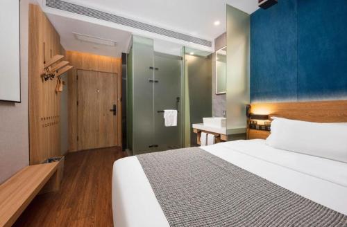 a bedroom with a large white bed and a bathroom at New Beacon Sunyee SPA Hotel in Wuhan