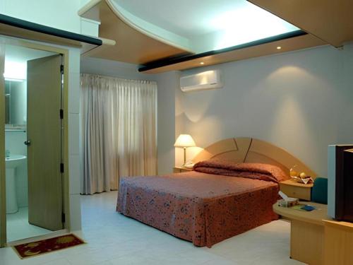 a bedroom with a bed and a bathroom with a television at Hotel Tower Inn, Chittagong in Chittagong