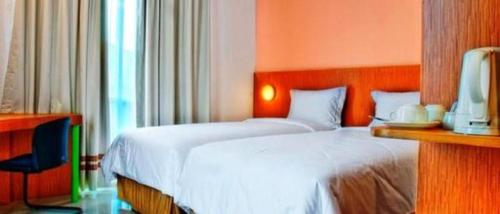 a hotel room with a bed and a chair at Pomelotel Patra Kuningan Jakarta in Jakarta