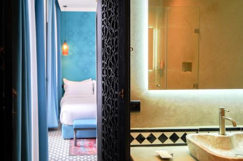 a bathroom with a sink and a mirror and a bed at Riad Looma in Marrakesh