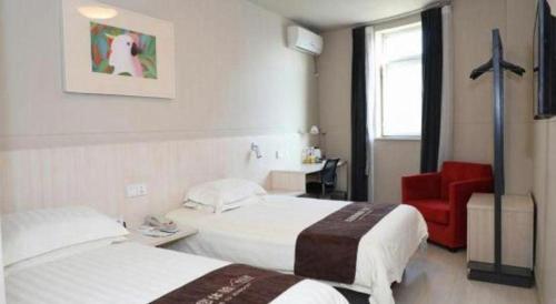 a hotel room with two beds and a red chair at Jinjiang Inn Changchun Xi An Avenue Branch in Changchun