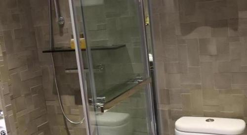 a bathroom with a toilet and a glass shower at M1 North Point Hotel in Hong Kong