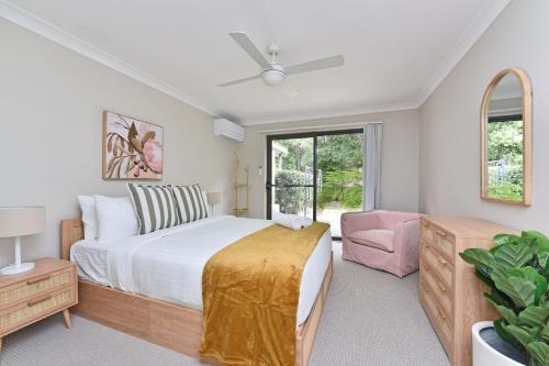 a bedroom with a large bed and a pink chair at Cleopatra's Oasis at Lagoon Estate in Nelson Bay