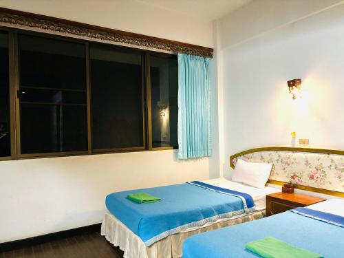 a bedroom with two beds and a window at โรงแรมรอยัลจอมมณี เฮอริเทจ in Ban Na Kai