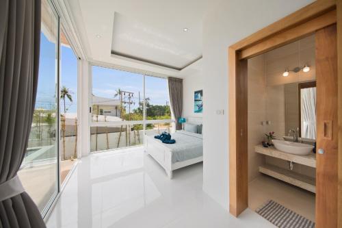 a bedroom with a bed and a bathroom with a window at Villa Namo Chaweng 2 Bed Garden Pool in Koh Samui