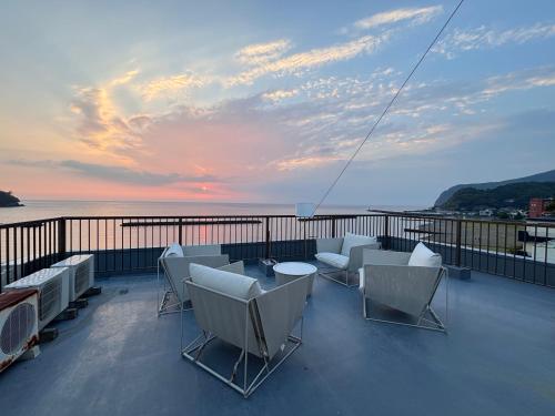 a balcony with chairs and a table and a sunset at Alim STAY IZU アリムステイ 伊豆 in Toi