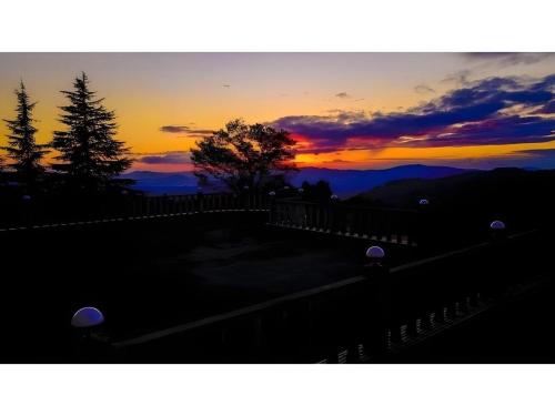 a sunset in the mountains with a fence and trees at HOTEL WINDSOR in Nakatsugawa