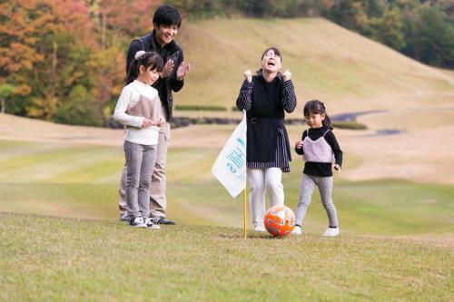 a group of children playing with a soccer ball on a golf course at HOTEL WINDSOR in Nakatsugawa