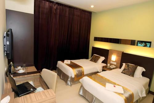 a hotel room with two beds and a desk with a laptop at Uptown Imperial Kajang in Kuala Lumpur